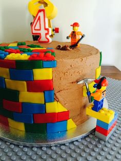 a birthday cake made to look like legos with the number four on top and two figures