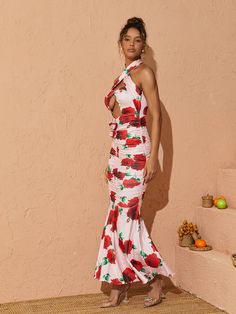 a woman in a white and red floral print dress posing for the camera with her hands on her hips