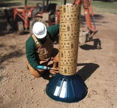 a man kneeling down next to a tall pole with numbers on it's sides