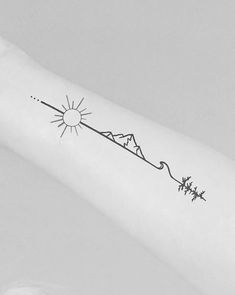 a person with a tattoo on their arm that has the sun and mountains in it