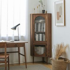 a wooden cabinet sitting next to a window in a room with white walls and wood floors