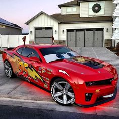 a red sports car with lightning bolt painted on it's hood parked in front of a house