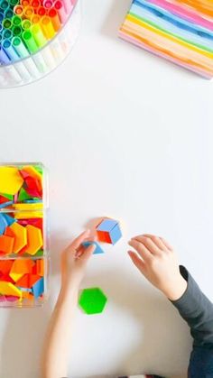 a young boy playing with colored blocks on the floor in front of a white wall