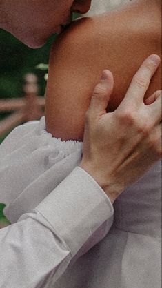 a woman in a white dress is holding her neck