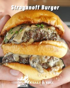 a person holding a hamburger in their hand with the words stroganoff burger on it