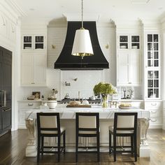 a kitchen with two chairs and an island in the middle, surrounded by white cabinets