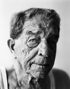 an old woman with wrinkles on her face and shoulders, looking at the camera