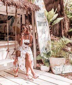 a woman sitting on a porch talking on a cell phone and holding a purse in her hand