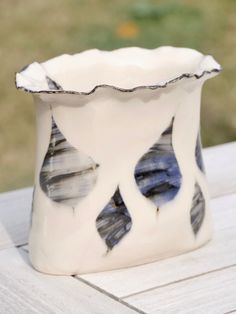 a white and blue vase sitting on top of a wooden table with grass in the background