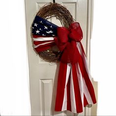 a wreath with an american flag on it hangs from the front door, next to a red and white bow