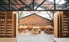 the inside of a building with wooden tables and benches in front of brick walls that have shelves on each side