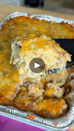 a casserole dish with meat and cheese being lifted from the pan by a spatula