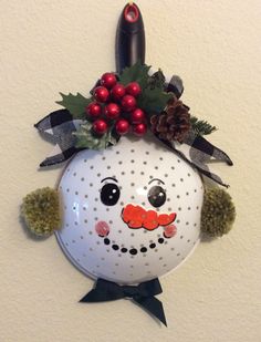 a christmas decoration with a snowman face and holly berry decorations on it's head