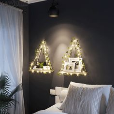 two triangle shaped lights are hanging on the wall above a bed in a dark room