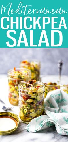 two jars filled with chickpea salad sitting on top of a table