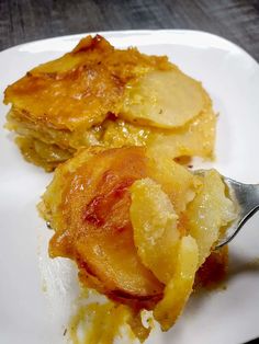 a white plate topped with food on top of a wooden table next to a fork