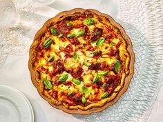 a pizza sitting on top of a white table cloth next to a plate and silverware