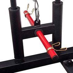 a red and black object is in the middle of two poles with hooks on them