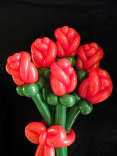 a vase filled with red flowers sitting on top of a black table next to a wall