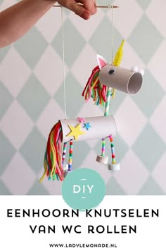 a hand holding a paper roll unicorn ornament with the words diy on it