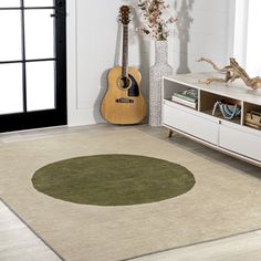 a living room with an area rug that has a guitar and vase on the floor