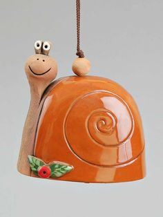 a ceramic snail ornament hanging from a cord with eyes on it's back