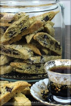 chocolate chip cookies in a glass jar next to a cup and saucer