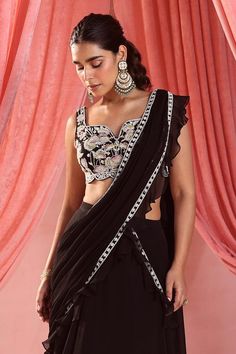 Black attached cancan layered pre-draped lehenga saree with floral embroidery on the skirt and a ruffle border. Paired with a floral embroidered blouse.
Components: 2
Pattern: Embroidered
Type Of Work: Sequin, Pearl, Glass Bead, Zari, Floral Applique
Neckline: Leaf
Sleeve Type: Sleeveless
Fabric: Saree: Organza and Georgette, Blouse: Georgette, Lining: Satin
Color: Black
Occasion: Sangeet - Aza Fashions Black Sequin Saree, Draped Lehenga, Drape Lehenga, Lehenga With Blouse, Saree Organza, Leaf Sleeve, Drape Saree, Georgette Blouse, Black Saree