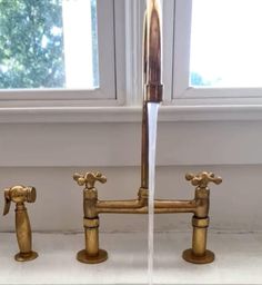 two faucets running water in front of a window