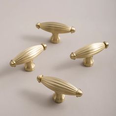 four brass door knobs on a white surface