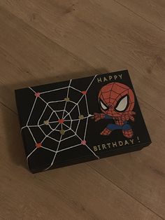 a spiderman birthday card sitting on top of a wooden floor