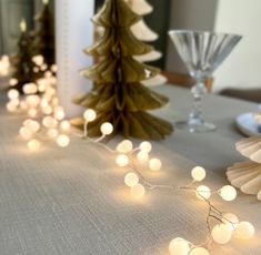 the table is decorated with white lights and paper trees on it, along with other holiday decorations