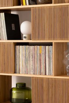 a wooden shelf filled with lots of records and vases on top of each other