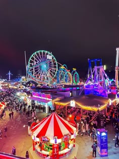 an amusement park at night with ferris wheel and fairgrounds in the foreground