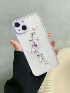 a woman is holding up her phone case with flowers on the front and back cover