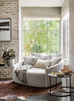 a living room filled with furniture next to a brick wall covered in plants and trees