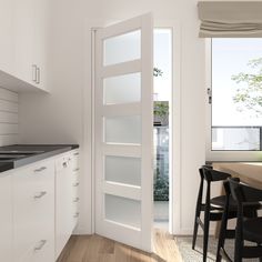 an open door leading to a kitchen with white cabinets and black counter tops on the side