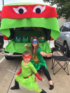 a woman and child dressed up as teenage mutant turtles in front of a truck with their costumes on