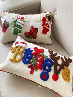 two christmas pillows sitting on top of a couch