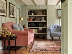 a living room with two chairs and a rug in front of the bookshelf