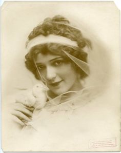 an old photo of a woman holding a bird in her hand and wearing a veil