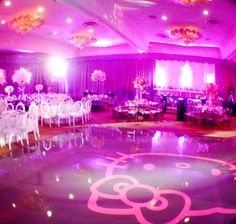 a large hello kitty dance floor is decorated with white chairs and pink lights in the background