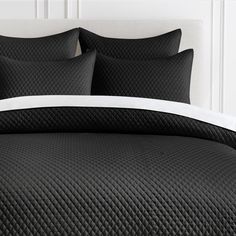 a bed with black quilting and white pillows