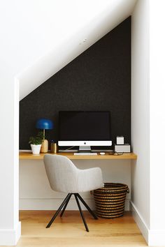 a desk with a computer on it under a slanted wall in an attic space