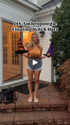 a woman is standing on steps holding a witches hat