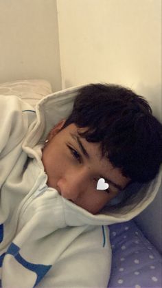 a young boy laying on top of a bed under a blanket