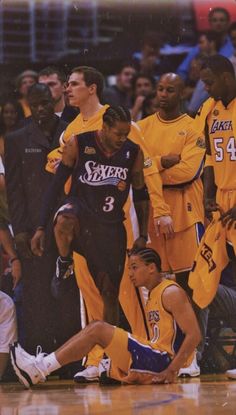 the basketball players are on the court and one is falling to the ground while others look on