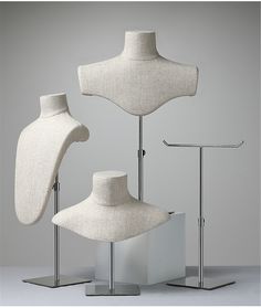 three white mannequins are standing on metal stands