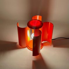 an orange lamp sitting on top of a table next to a white wall and floor