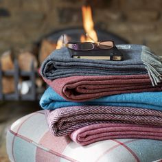 a stack of folded blankets sitting on top of a chair next to a fire place